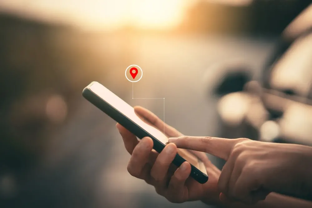 Close up of person using their smartphone with a graphic overlayed showing a location pin